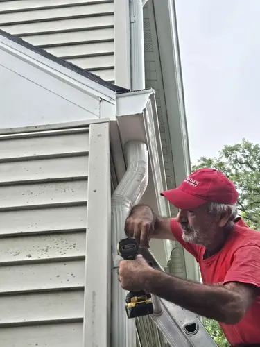 Professional gutter installation in progress - Need: 800x600px image showing technician installing new gutters on residential home